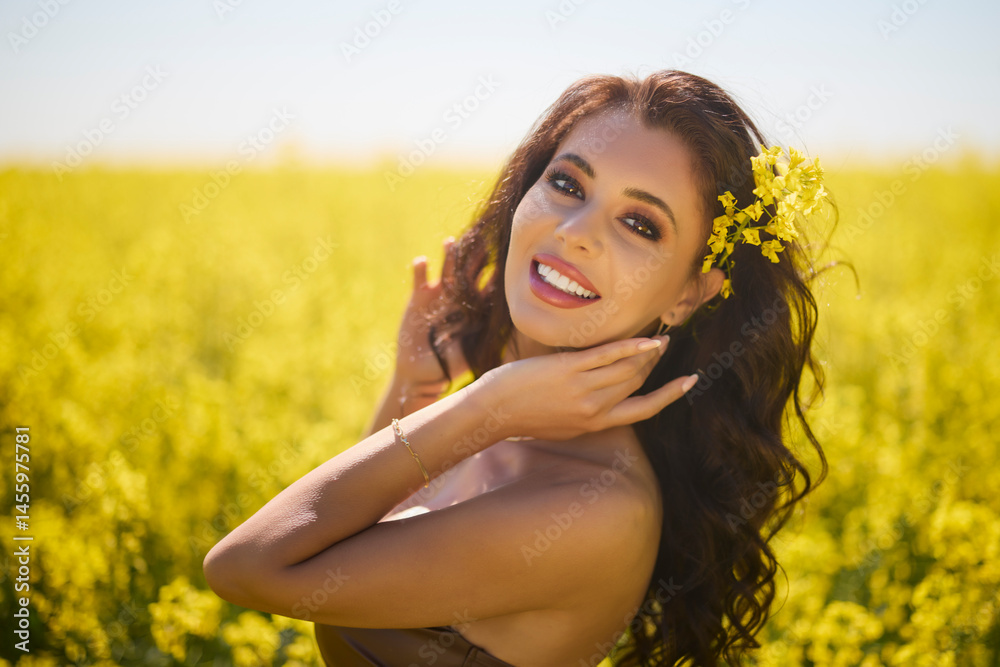 beautiful woman posing in a field of blooming rapeseed