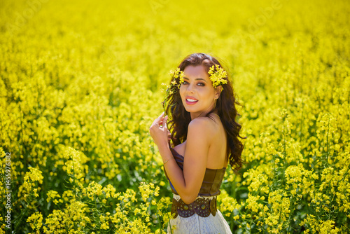 Obraz na płótnie beautiful woman posing in a field of blooming rapeseed w salonie