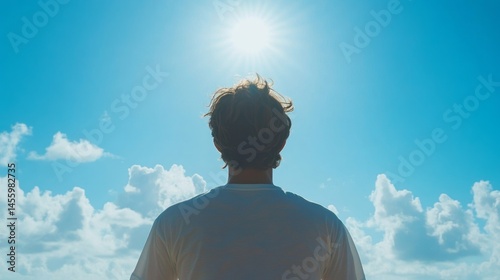 A person gazes upwards at a bright, sunny sky.