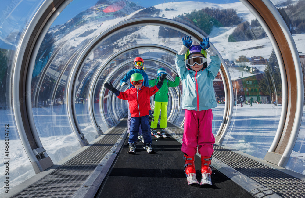Several people kids and adults skiers in transparent tunnel lift