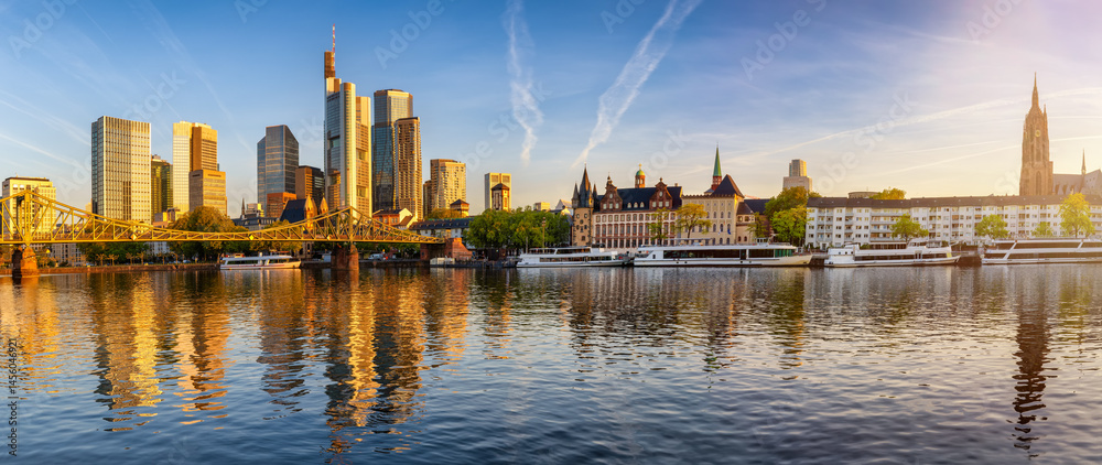 Panoramic view of the skyline of Frankfurt am Main, Germany, with Eiserner Steg bridge, office skyscrapers and Kaiserdom church during a golden sunrise