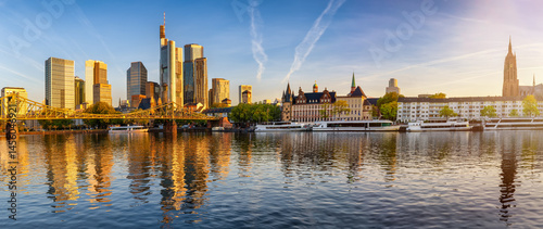 Obraz na płótnie Panoramic view of the skyline of Frankfurt am Main, Germany, with Eiserner Steg bridge, office skyscrapers and Kaiserdom church during a golden sunrise w salonie