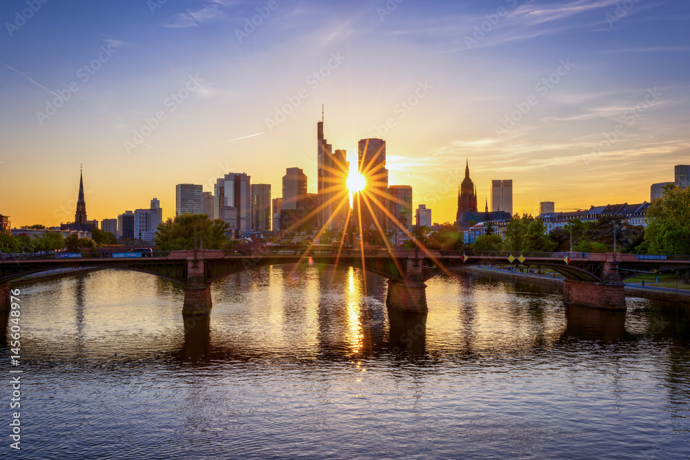 Sunset view of the modern skyline of Frankfurt, Germany, with the sun setting exactly behind the financial skyscrapers