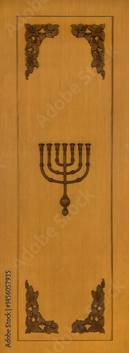 Close up of wood ornamental frame with The menorah symbol in the middle. Menorah is a seven branched candle used in Judaism and Christianity in a tabernacle for God.  Religious carving symbols. photo