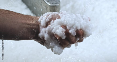 Super Slow Motion Close-Up of Artisan Hand Holding Wet Pulp During Handmade Paper Production Process Inside a Traditional Workshop with Machinery in Background 1000 fps.
