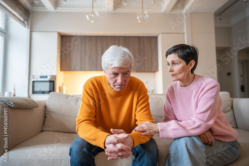 Fotografie Worried wife supporting husband in emotional distress on sofa