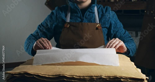 Super Slow Motion of Handmade Paper Sheet Being Carefully Handled on a Wooden Surface, Showcasing Its Texture, Deckled Edges, and Natural Imperfections in a Craft or Artistic Studio Environment.