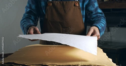 Super Slow Motion of Handmade Paper Sheet Being Carefully Handled on a Wooden Surface, Showcasing Its Texture, Deckled Edges, and Natural Imperfections in a Craft or Artistic Studio Environment.