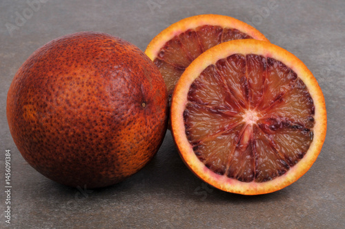 Orange sanguine entière et orange sanguine coupée en deux en gros plan isolées sur fond gris