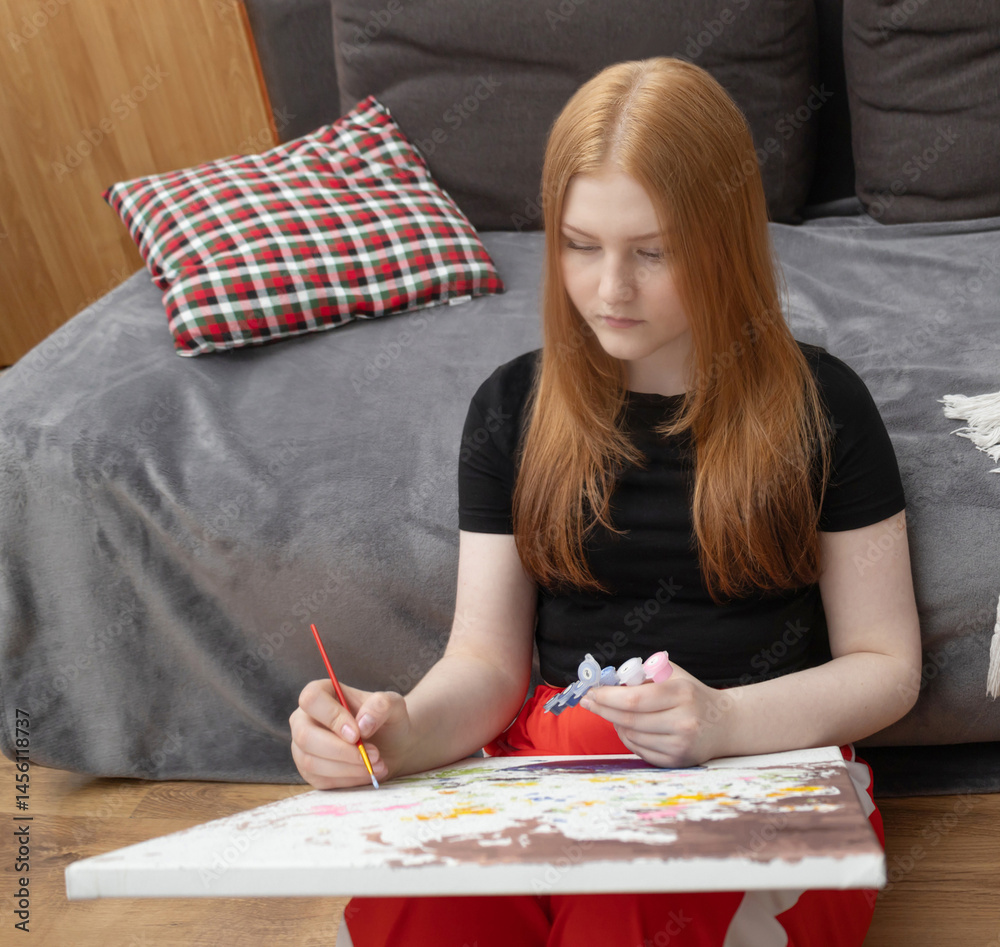 girl sitting on the floor at home and painting a picture by numbers painting by numbers