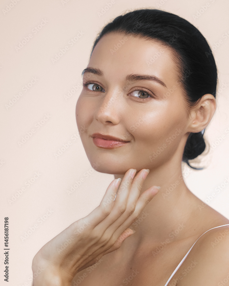 A stunning young woman with radiant skin applying moisturizer to her face. Concept of beauty, skincare, and self-care, ideal for wellness and beauty product advertisements.