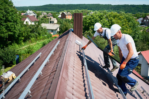 Wallpaper Mural Workers building solar panel system on roof of house. Two men installers in helmets carrying photovoltaic solar module outdoors. Alternative, green and renewable energy generation concept. Torontodigital.ca