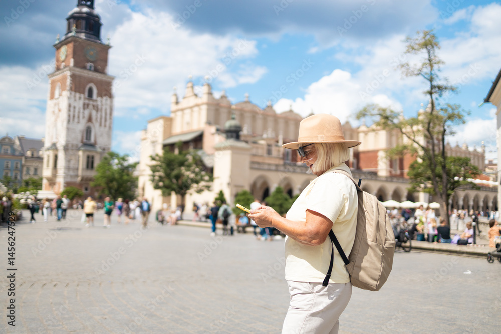 A senior woman stands in a beautiful city square, holding a map while enjoying sightseeing. She is dressed in a comfortable outfit, wearing a hat and sunglasses.