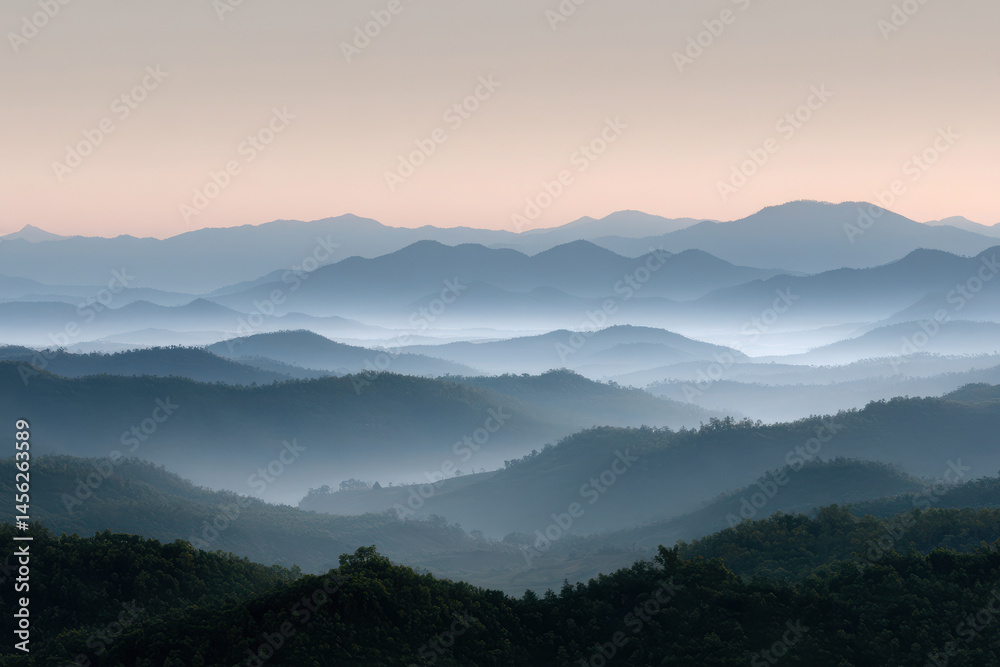 Obraz premium majestic mountain ridges at dawn enveloped in light fog with soft warm light illuminating peaks