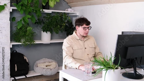 millennial man in stylish casual clothes using smartphone and computer while spending time at home