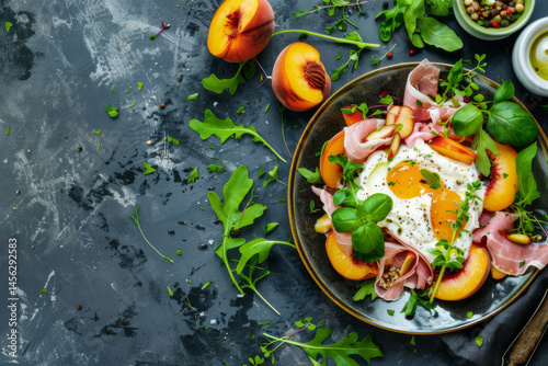 Obraz na płótnie A gourmet breakfast plate with sunny side up eggs, prosciutto, peaches, and fresh greens on a dark slate background. w salonie