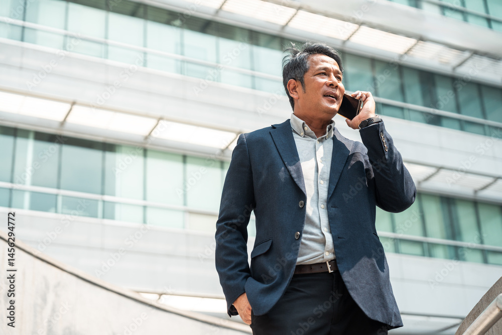 Senior manager business man in suit with cell phone at the buildings downtown. Confident man using smartphone looking towards their goals for success. Executive business man Senior manager business man in suit with cell phone at the buildings downtown. Confident man using smartphone looking towards their goals for success. Executive business man