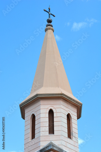 Obraz na płótnie A close-up shot features the bell tower of St. James Church in Jadranovo, topped with a cross against a clear blue sky w salonie