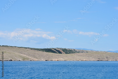 Obraz na płótnie A serene view from Jadranovo shows the rugged coastline of Krk Island meeting the calm blue waters under a partly cloudy sky w salonie