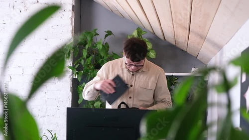 millennial man in stylish casual clothes packing his bag working in the office