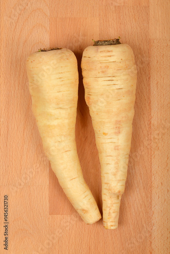Obraz na płótnie Two beige parsnips are positioned parallel on a light brown wooden surface w salonie