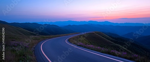 Winding asphalt road through rolling hills at scenic twilight mountain pass