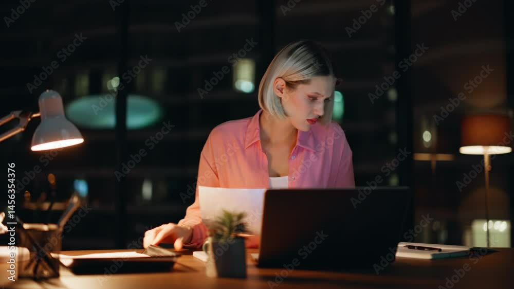 Hardworking manager working night workplace handling paperwork. Serious woman Hardworking manager working night workplace handling paperwork. Serious woman