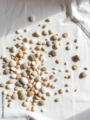 Pebbles scattered across a white linen surface in a haphazard manner, eclectic, natural