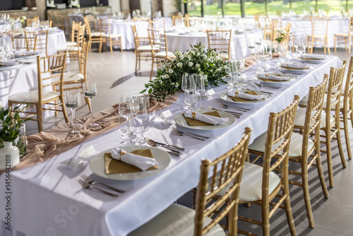 A wedding table covered with a white tablecloth, decorated with flowers, cand...