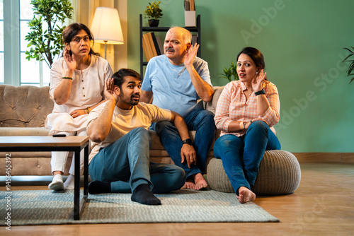 Looking at camera, Indian family laughs while covering ears to react to funny gossip together