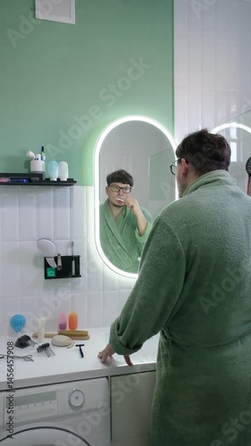 man brushing his teeth in front of a Mirror in the bathroom