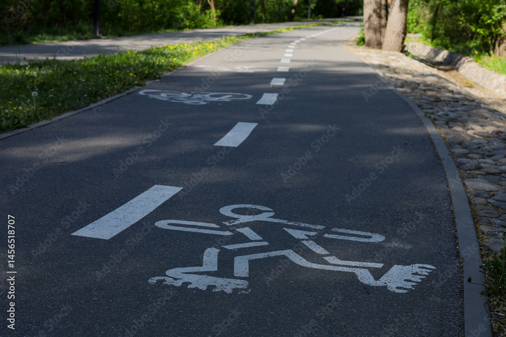 Obraz premium Markings on a path in a city park. The path is intended for rollerblading. The oncoming path is intended for cyclists.