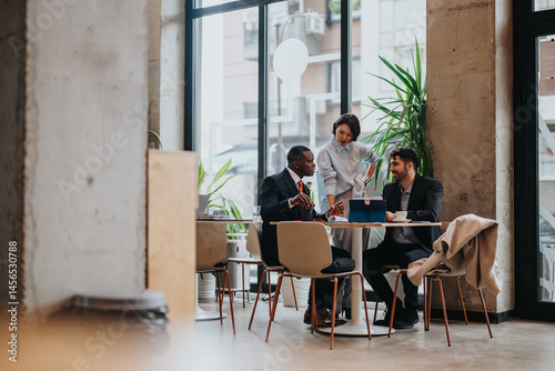 Three colleagues engage in a productive business discussion at a table in a contemporary, well-lit co working office environment, symbolizing teamwork and professional collaboration.