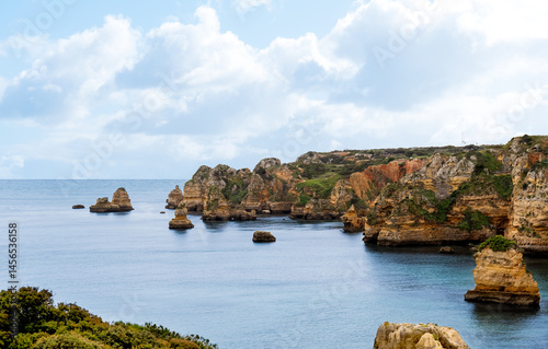 Coastal path along cliff top stunning view of hidden coves,blue ocean and rock formations. Seascape blue sky,cloudover atlantic sea in sunny day summer at Praia da Marinha,Marinha in Algarve, Portugal