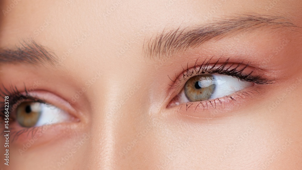 Macro close-up of a woman s eyes with soft peach eyeshadow and smooth skin texture. Ideal for eye care, facelift, skincare, or anti-aging cosmetic promotions. High detail beauty concept.