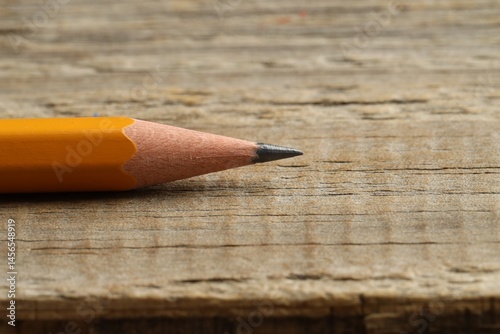 One sharp graphite pencil on wooden table, closeup. Space for text