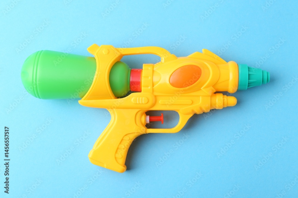 Bright plastic water gun on light blue background, top view Bright plastic water gun on light blue background, top view
