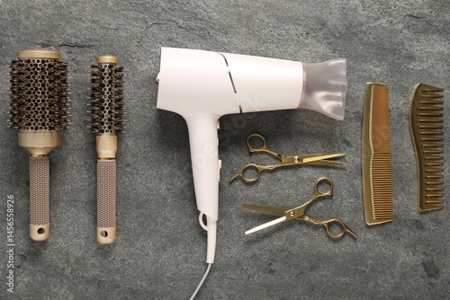 Different hairstyling tools on grey textured background, flat lay