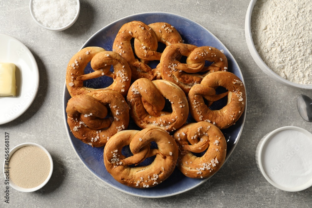 Naklejka premium Tasty pretzels and ingredients on grey table, flat lay