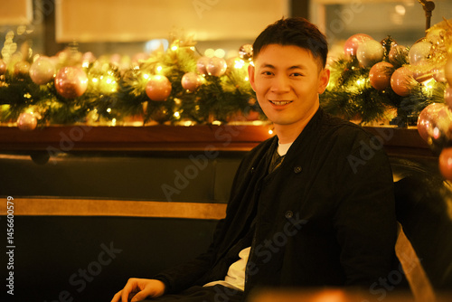 Asian young man smiling at camera with Christmas decoration at night