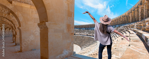 Happy woman in hat open arms in free happiness standing and posing -  Roman amphitheater of Aspendos, Belkiz - Antalya, Turkey photo