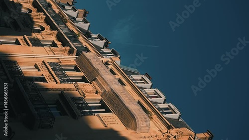 Ancient house with attic flats and openwork lattices on balconies. Unique architecture with stucco on facade. Trace of airplane high in sky. Slow motion. Low angle shooting. Vertical video