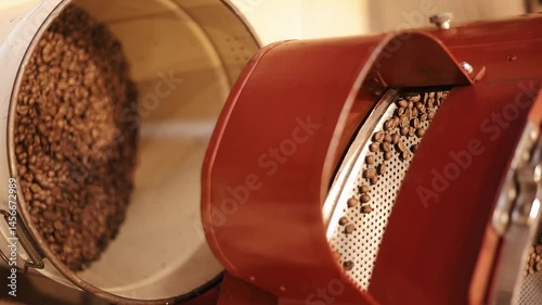 Coffee beans are poured into tank after roasting in production machine. Close-up. From cultivation to final consumer fruits undergo processing that negatively affects environment