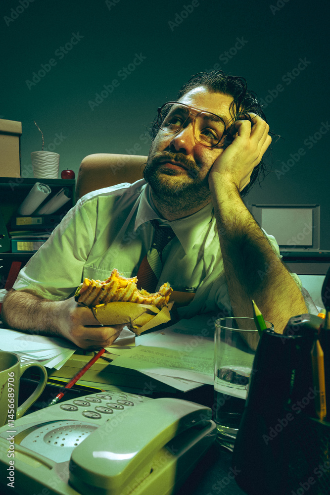 Daydreaming office worker holding sandwich, looks up with bored face at cluttered desk, showing fatigue, absurdity, nostalgia, pressure and corporate burnout. Concept of retro office , overwork