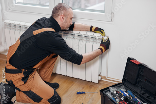 Obraz na płótnie Central heating mechanic and handyman fixing home radiator, gas crisis and seasonal issues. w salonie