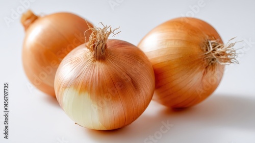 Wallpaper Mural Three whole yellow onions with dry skins are placed on a white surface, showing their roots and natural texture. Torontodigital.ca