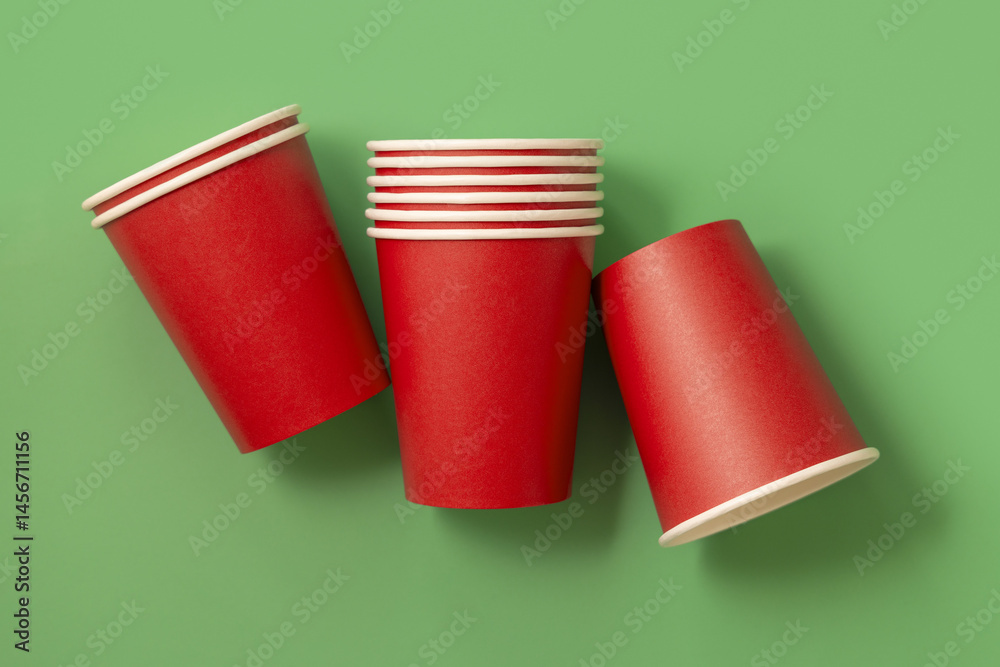 Disposable red paper cups on a green top view, mockup. No plastic and sustainable Christmas