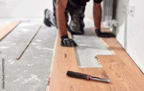 Professional handyman installing laminate flooring in a new apartment.