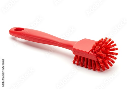 A red dish brush with a handle and bristles on a white background in a studio setting for cleaning dishes