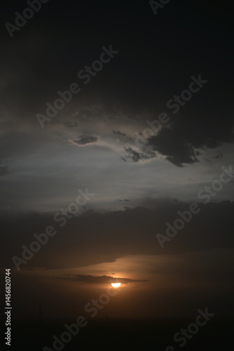 The dark clouds, setting sun and sandstorm weather above the city of Turpan